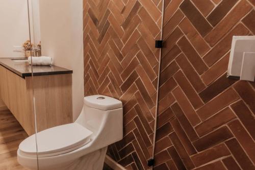 a bathroom with a toilet and a wooden wall at Spacious Apartment with Balcony in El Zonte