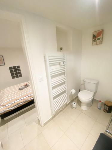 - une salle de bains blanche pourvue de toilettes et d'un lit dans l'établissement Logement à 20 mins de paris , Stade 2 France, Aéro CDG, Parc des expositions, à Arnouville-lès-Gonesse