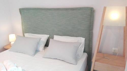 a bed with white pillows and a green headboard at Top Studios in Vourvourou