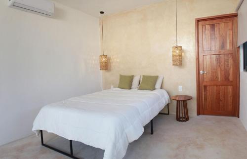 a bedroom with a white bed and a wooden door at Casa Dzunun in Santa Clara