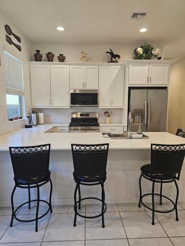 a kitchen with white cabinets and black chairs at genie palace at statefarm stadium in Phoenix