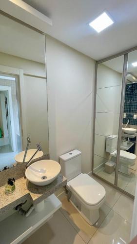 a bathroom with a toilet and a sink and a mirror at Apartamento Luxo Centro com Suíte, Sacada, Garagem, Garage in Jaraguá do Sul