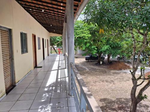 a porch of a building with a fence and trees at Pousada Rio Munim Presidente Juscelino Ma in Morros
