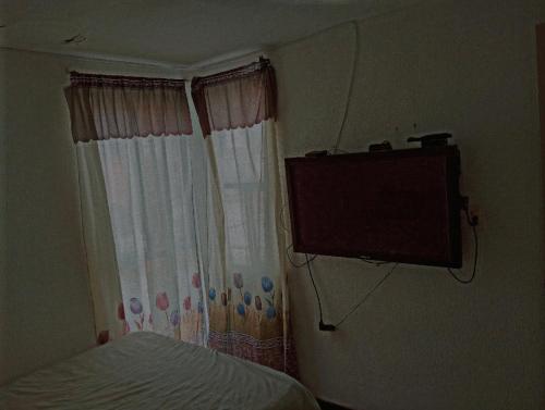 a bedroom with a bed and a television on the wall at Cómo en Casa in San Juan Xilotzingo