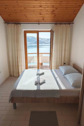 a bedroom with a bed with a view of the ocean at Apartments by the sea Stara Novalja, Pag - 13938 in Stara Novalja