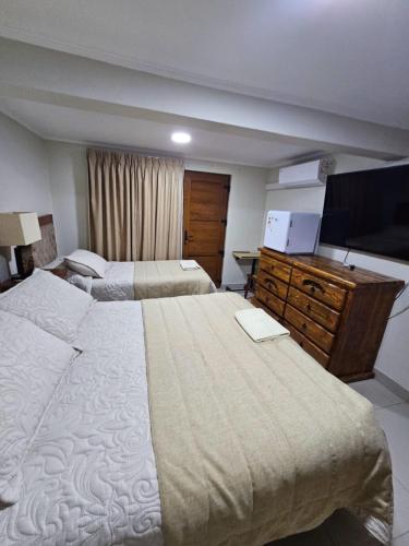 a hotel room with two beds and a flat screen tv at Hostal Aires del Sur Renovado in Rancagua