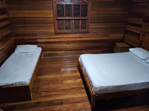 two beds in a room with wooden walls at Recanto Gu&Gui in Camanducaia