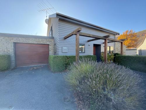 a house with a garage door and a building at Chartres Retreat in Arrowtown