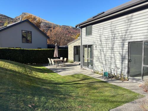 a patio with a table and an umbrella next to a house at Chartres Retreat in Arrowtown