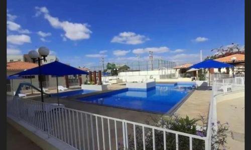a large swimming pool with blue umbrellas on a patio at Condomínio São Francisco in Petrolina