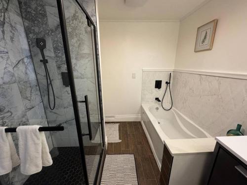 a bathroom with a shower and a bath tub at The Urban Nest - Windsor in Windsor