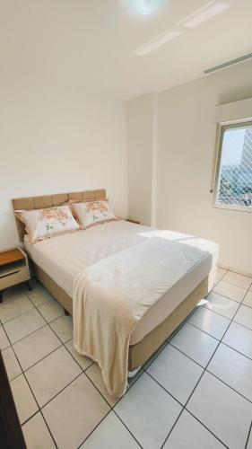 a bedroom with a large bed in a white room at Apartamento privativo centro do centro 2 quartos Com ar e garagem in Jaraguá do Sul