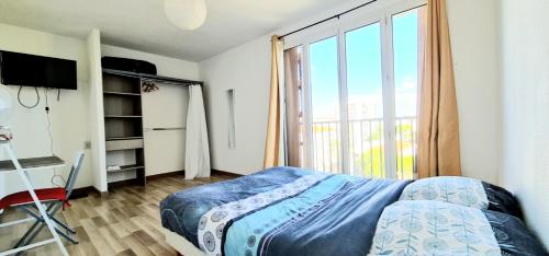 une chambre avec un lit et une grande fenêtre dans l'établissement Appartement Standing 110m2 lumineux, Clim, balcons, à Perpignan