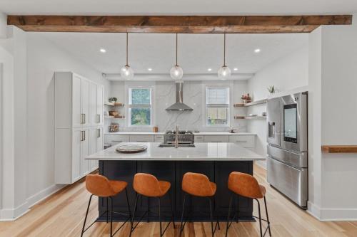 a kitchen with a large island with orange chairs at 3BR Stylish Retreat, Minutes from Downtown Pittsburgh, Free 3-Car Parking in Pittsburgh
