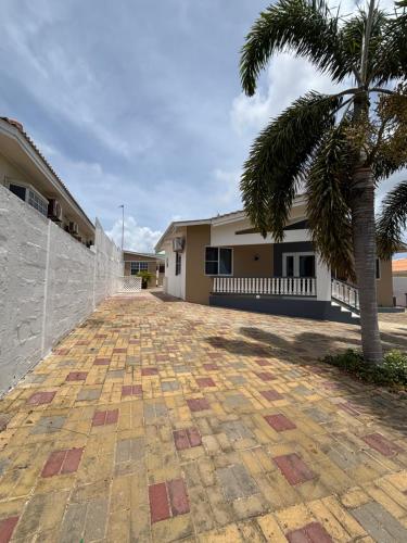 a driveway with a palm tree and a building at Aqua Villa in Willemstad