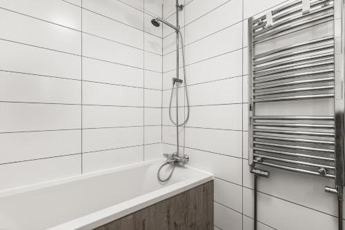 a shower in a bathroom with white tile walls at Perfect spacious 2-bedroom apartment near Sky Lagoon in Reykjavík