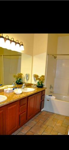 Un baño con dos lavabos, una bañera y un espejo. en Club de Soleil, en Las Vegas