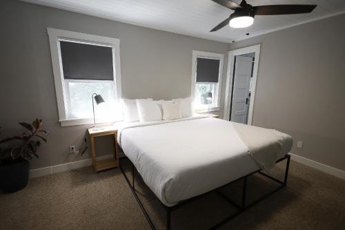 a bedroom with a white bed with a lamp and two windows at Piety Hill Cottages in Nevada City