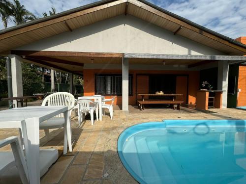 a pavilion with tables and chairs and a swimming pool at Casa espetacular com 5 quartos 50 metros do mar in Matinhos