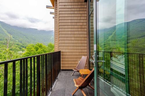 a balcony with two chairs and a view of the mountains at Spruce Peak Resort luxury 3 Bedrm 2levelApartment in Stowe