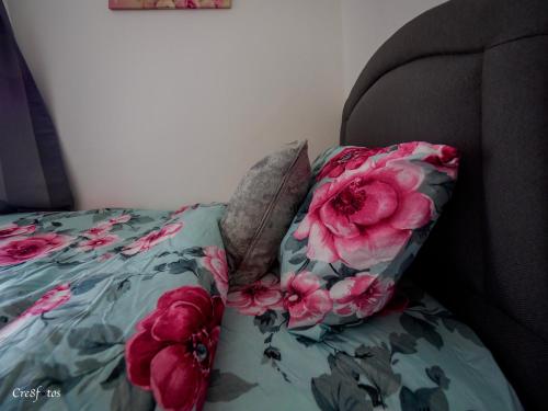 a bed with a pillow with pink flowers on it at Newlands Lodge Deluxe Family Room 2 in Stoke on Trent