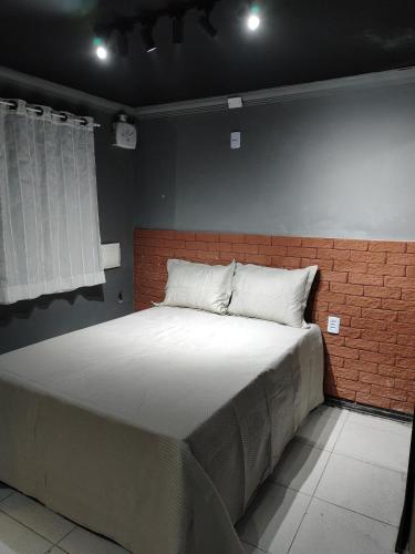 a large bed in a room with a brick wall at Loftjesus in Campina Grande