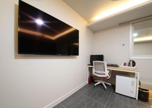 an office with a desk and a large television on the wall at Gwangju Yeogijoa Hotel in Gwangju