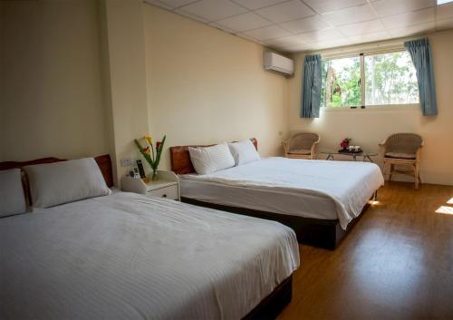 um quarto de hotel com duas camas e uma janela em Nantou Fruit House em Renai