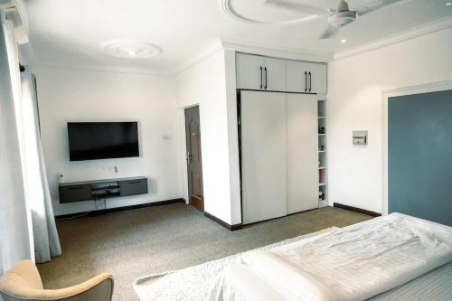 a white bedroom with a bed and a flat screen tv at The Space in Adentan