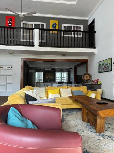 a living room with a yellow couch and a wooden table at The Space in Adentan