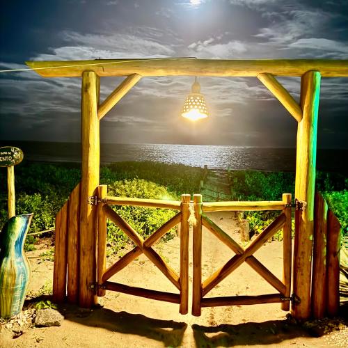 a wooden gate with a view of the ocean at JaParaíso Pousada Ateliê in Japaratinga