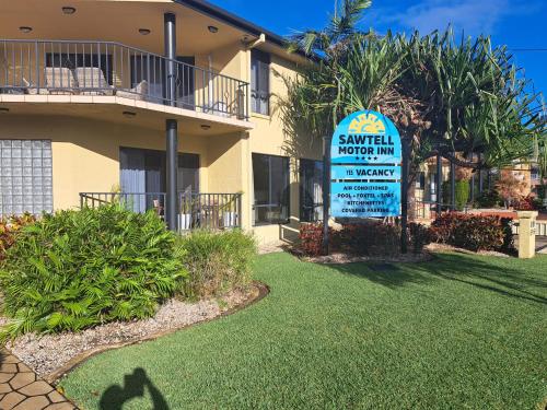 a sign in front of a house with a yard at Sawtell Motor Inn in Sawtell