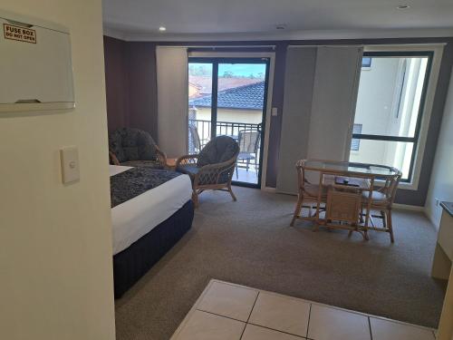 a hotel room with a bed and a table and chairs at Sawtell Motor Inn in Sawtell