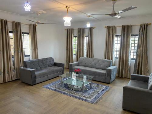 a living room with two couches and a glass table at Joemat Lodge in Agboogba