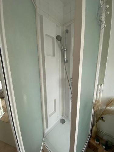 une cabine de douche dans une salle de bain blanche avec dans l'établissement Chambre chaleureuse dans une Mancelle, à La Celle-sous-Gouzon