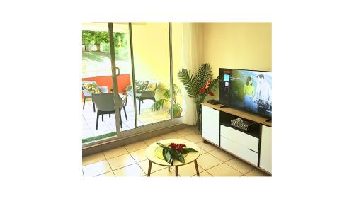 a living room with a television and a balcony at Prestige Lodging City Center in Papeete
