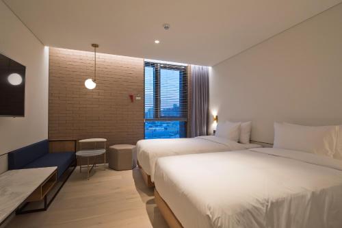 a hotel room with two beds and a window at Cont Hotel in Busan