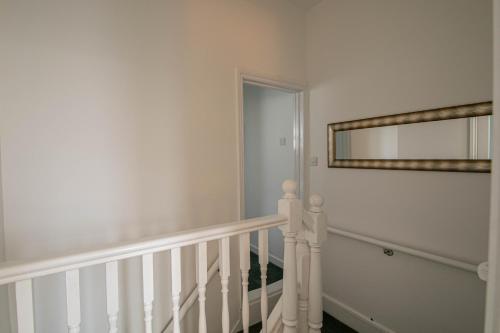 a white staircase with a mirror on the wall at 3 Bed Stylish & Spacious Home, Sleep up to 7ppl in Portsmouth