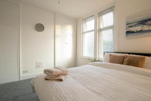 a white bedroom with a bed with a clock on the wall at 3 Bed Stylish & Spacious Home, Sleep up to 7ppl in Portsmouth