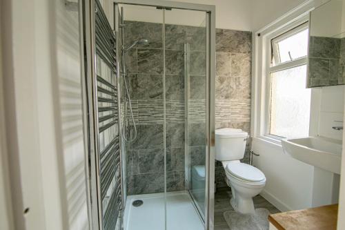 a bathroom with a toilet and a glass shower at 3 Bed Stylish & Spacious Home, Sleep up to 7ppl in Portsmouth
