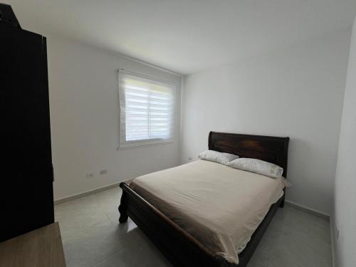a white bedroom with a bed with a window at Apartamento hogar para compartir con 3 habitaciones 3 piscinas, turco, sauna, gym y más en Restrepo Meta in Restrepo