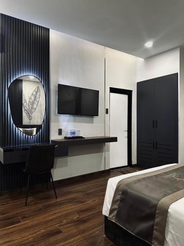 a bedroom with a bed and a desk and a television at LION 10 HOTEL in Can Tho
