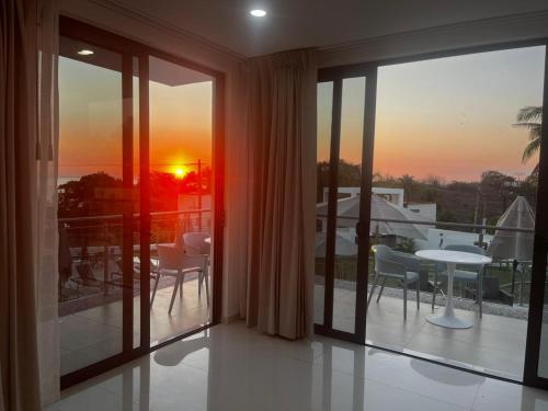 a balcony with a view of a sunset seen through windows at Villas Solemar, Aticama in Aticama