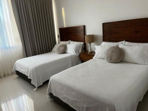 a hotel room with two beds and a window at Villas Solemar, Aticama in Aticama