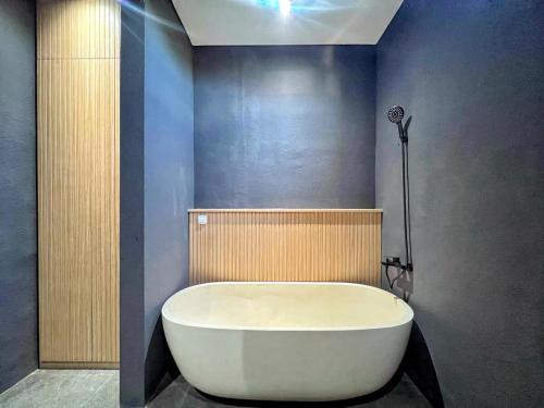 a white bath tub in a bathroom with a wall at Villa Shinta1 with 3 BR, Pool & WiFi in Ungasan Bali by Damaresa in Uluwatu
