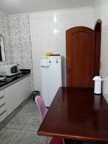 a kitchen with a table and a white refrigerator at Suíte no Morumbi in Sao Paulo