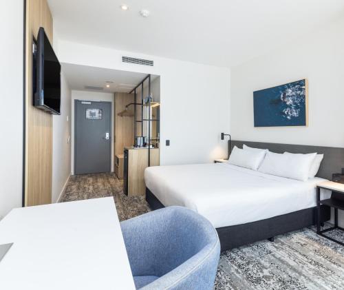 a hotel room with a bed and a chair at Oaks Cairns Hotel in Cairns