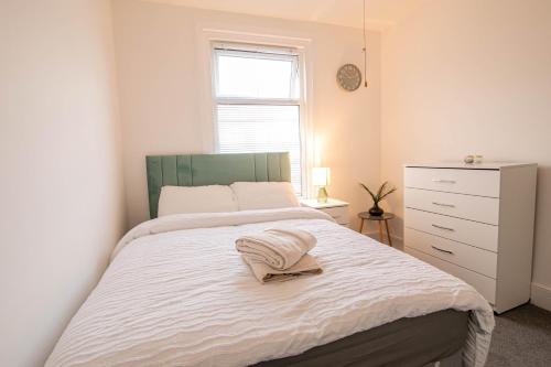 a bedroom with a white bed with a white dresser and a window at 3 Bed Stylish & Spacious Home, Sleep up to 7ppl in Portsmouth