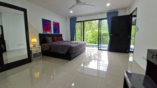 a bedroom with a bed and a large window at Private Valley View pool villa Phuket in Ban Klang