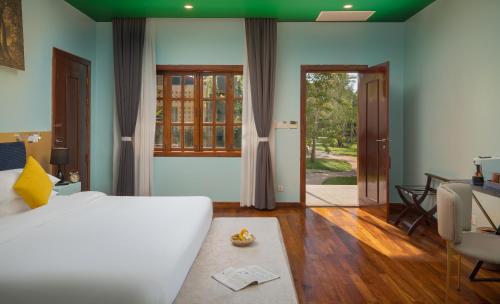 a bedroom with a bed and a table and a chair at Sala Siem Reap Resort in Siem Reap